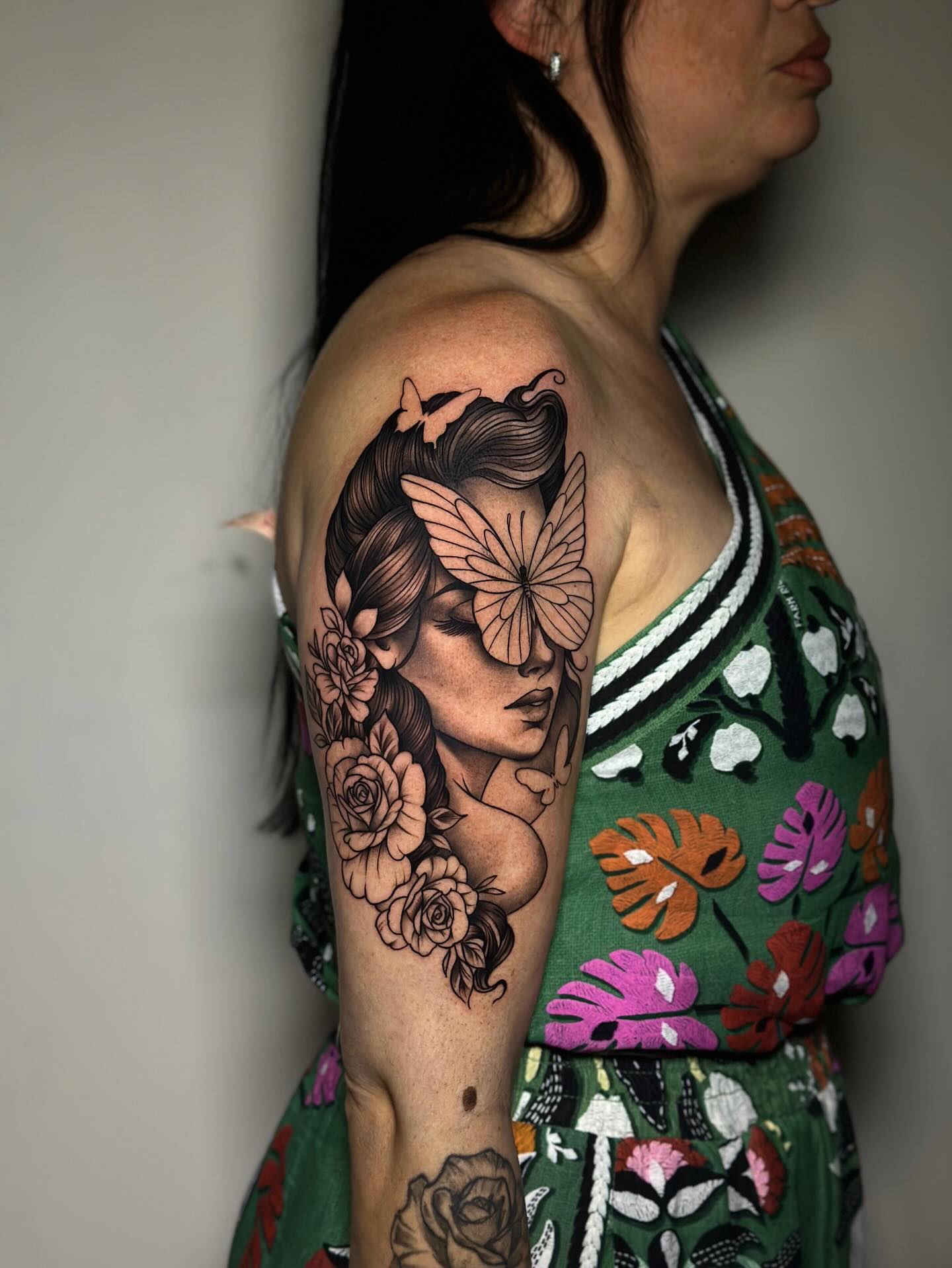 Tatuagem black and grey de mulher com borboletas e rosas no braço